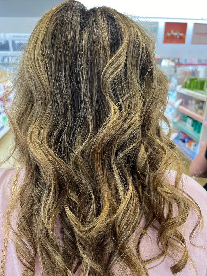 Long wavy hair with warm blonde balayage highlights, styled at CreativeFaces
